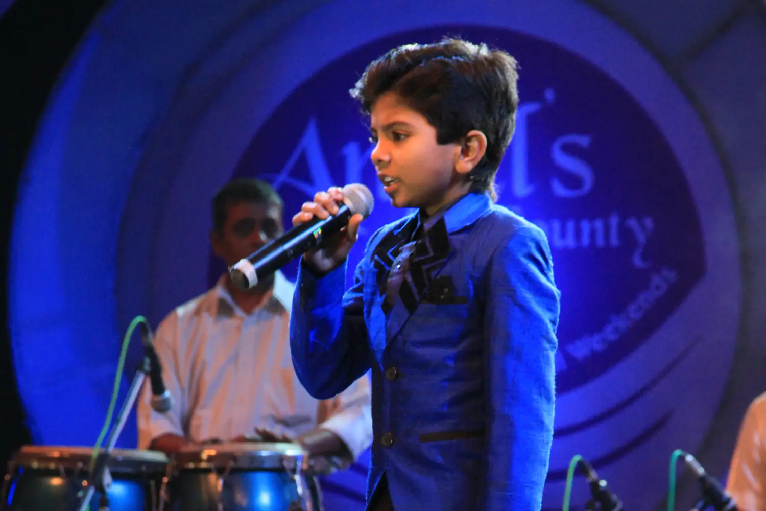 Man and woman speaking on stage at night with blue lighting